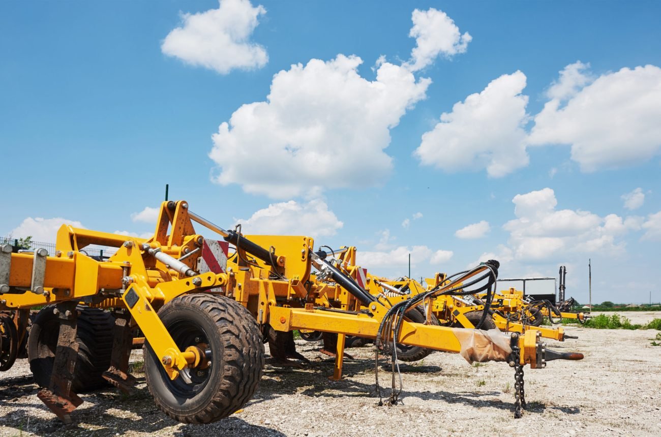 Close up of seeder attached to tractor in field. Agricultural machinery for spring works sowing, seeding