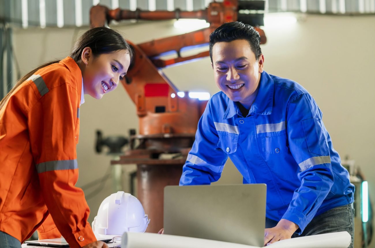 engineer cooperation Two asian male and female technician maintenance inspect relay robot system with tablet laptop to control quality operate process work heavy industry 4.0 manufacturing factory